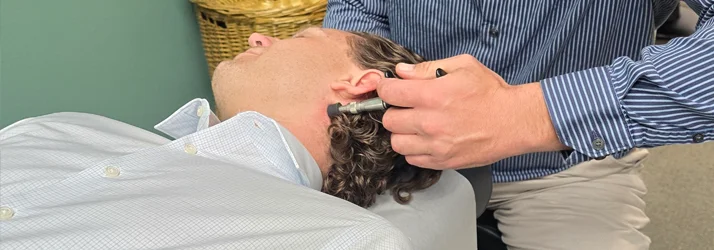 Chiropractor Grand Junction CO Ron Engler Dr. Ron Engler performing a neck adjustment on a patient using an activator tool